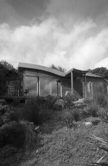 Picture from the garden looking up at the extensions wave roof and glazed frontage in black and white