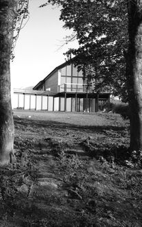Pictured from the trees the back completely glazed facade of a replacement dwelling near Saltash in black and white