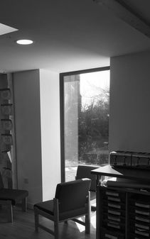 Internal picture of classroom chair by full height triple glazed window in black and white